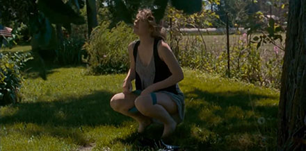 Woman urinating on the lawn in the garden